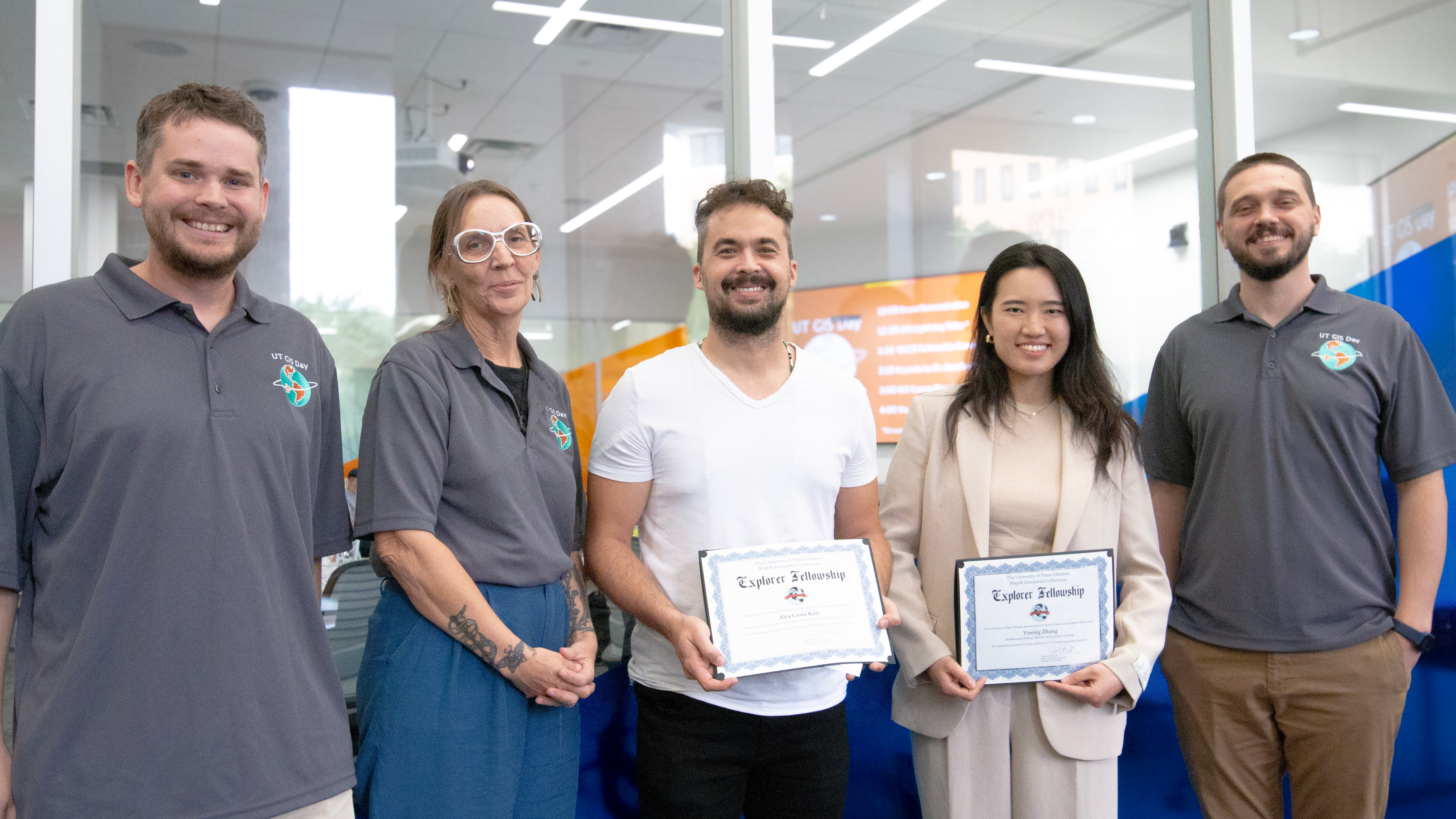 UT Libraries staff stand with the 2025 Map & Geospatial Collections Explorer Fellowship recipients, Alex Costa Kott and Yiming Zhang, who hold certificates recognizing their geospatial research projects.