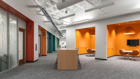 open space with orange huddle rooms and collaboration island