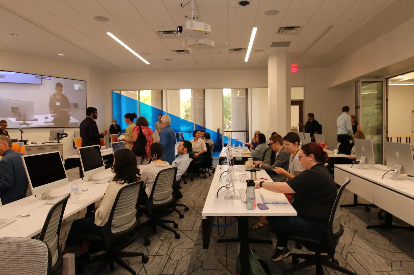 The Scholars Lab Data Lab with rows of desks, computers, and individuals facing the front where a presentation is taking place.