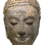 Image is a photo of the face of a stone statue. Statue has its eyes closed and a small smile.